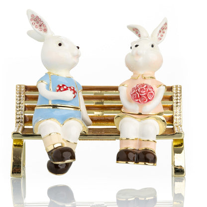 2 bunnies in love sitting on a bench, valentine flowers and chocolates by Keren Kopal