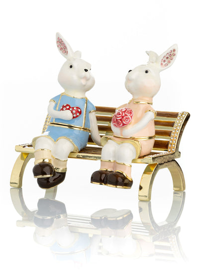 2 bunnies in love sitting on a bench, valentine flowers and chocolates by Keren Kopal