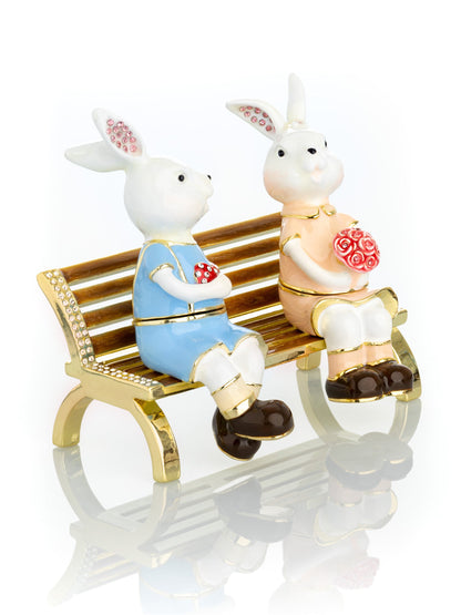 2 bunnies in love sitting on a bench, valentine flowers and chocolates by Keren Kopal