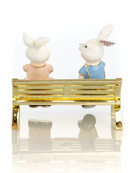 2 bunnies in love sitting on a bench, valentine flowers and chocolates by Keren Kopal