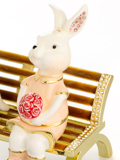 2 bunnies in love sitting on a bench, valentine flowers and chocolates by Keren Kopal