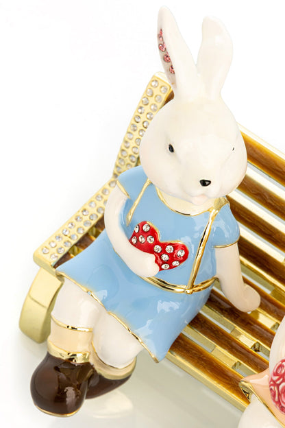 2 bunnies in love sitting on a bench, valentine flowers and chocolates by Keren Kopal